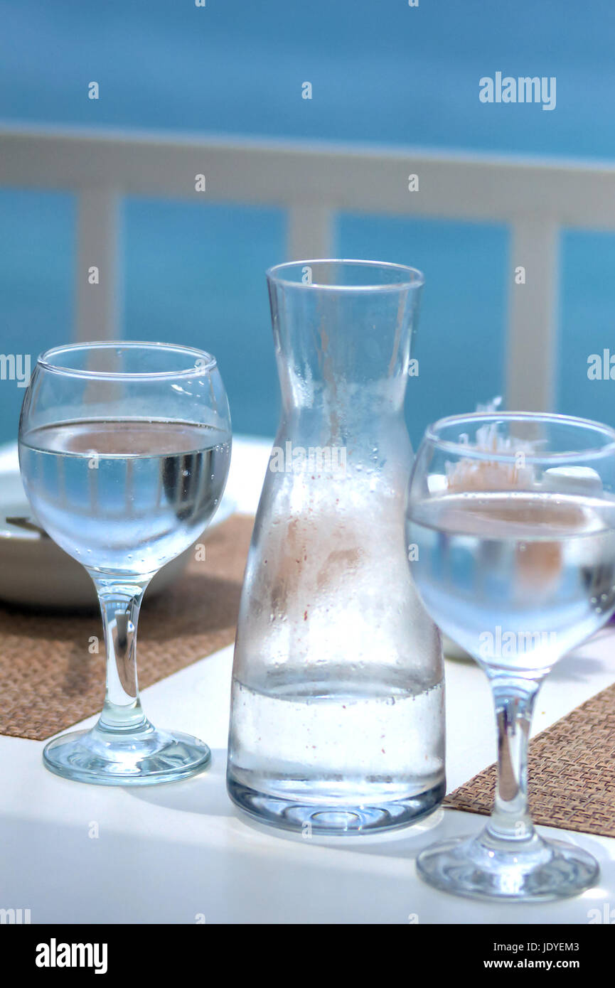 Wasserkaraffe und 2 Gläser mit Wasser auf Terrassentisch vor Meer Stock Photo