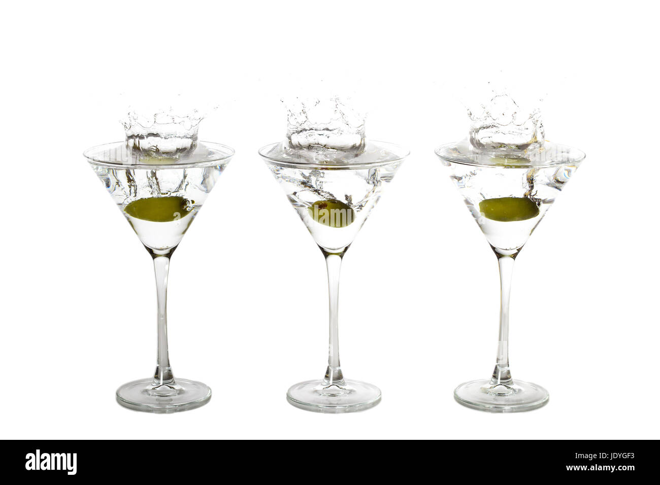 Olives splashing into three martini glases at the same time Stock Photo