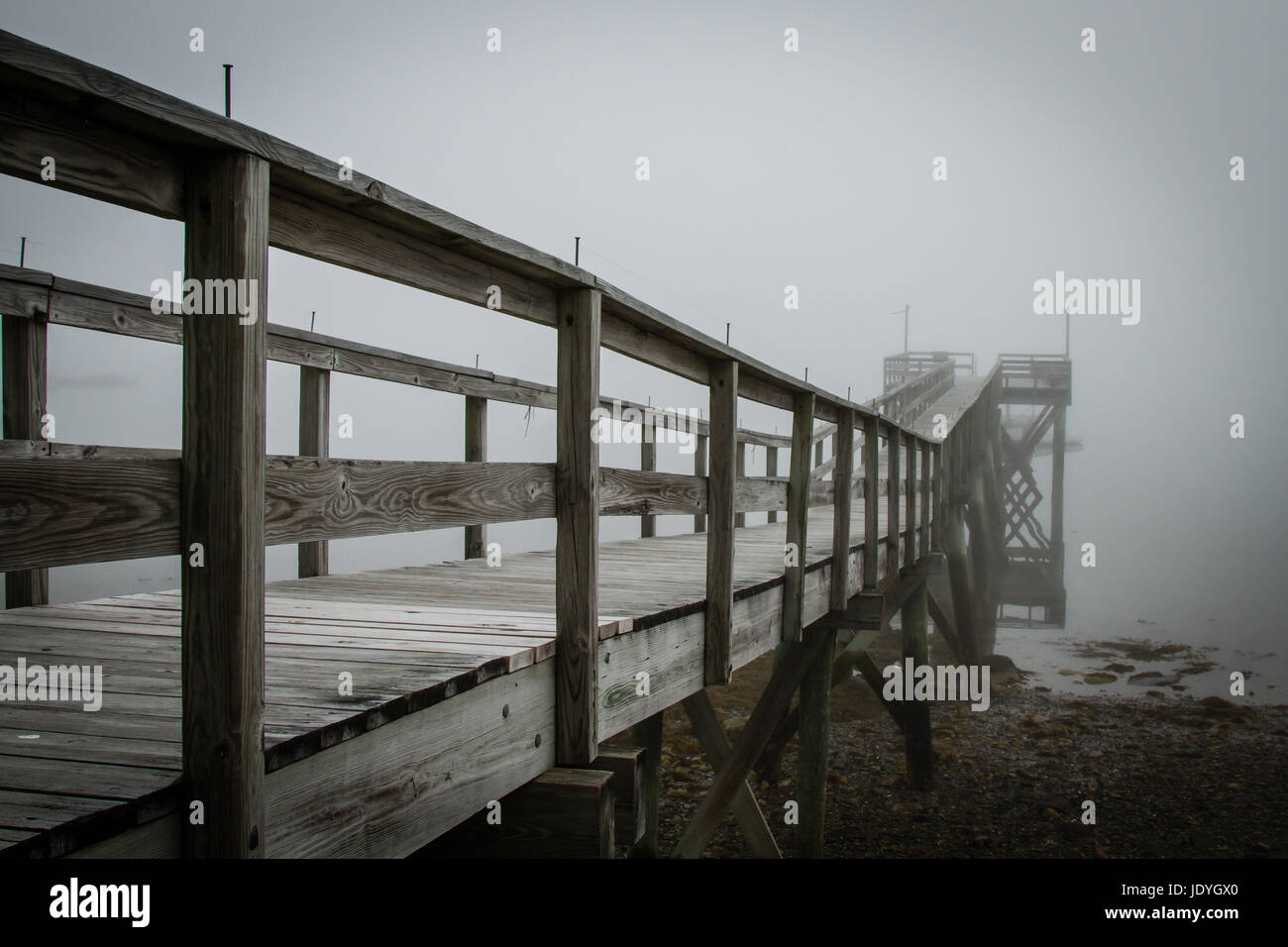 Long wooden pier on a foggy morning. Stock Photo