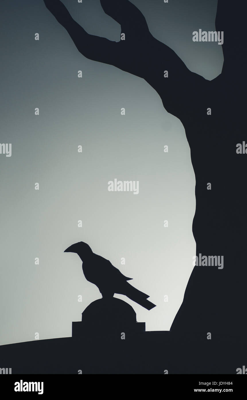 crow on tombstone in dark graveyard Halloween creative paper cutout landscape Stock Photo