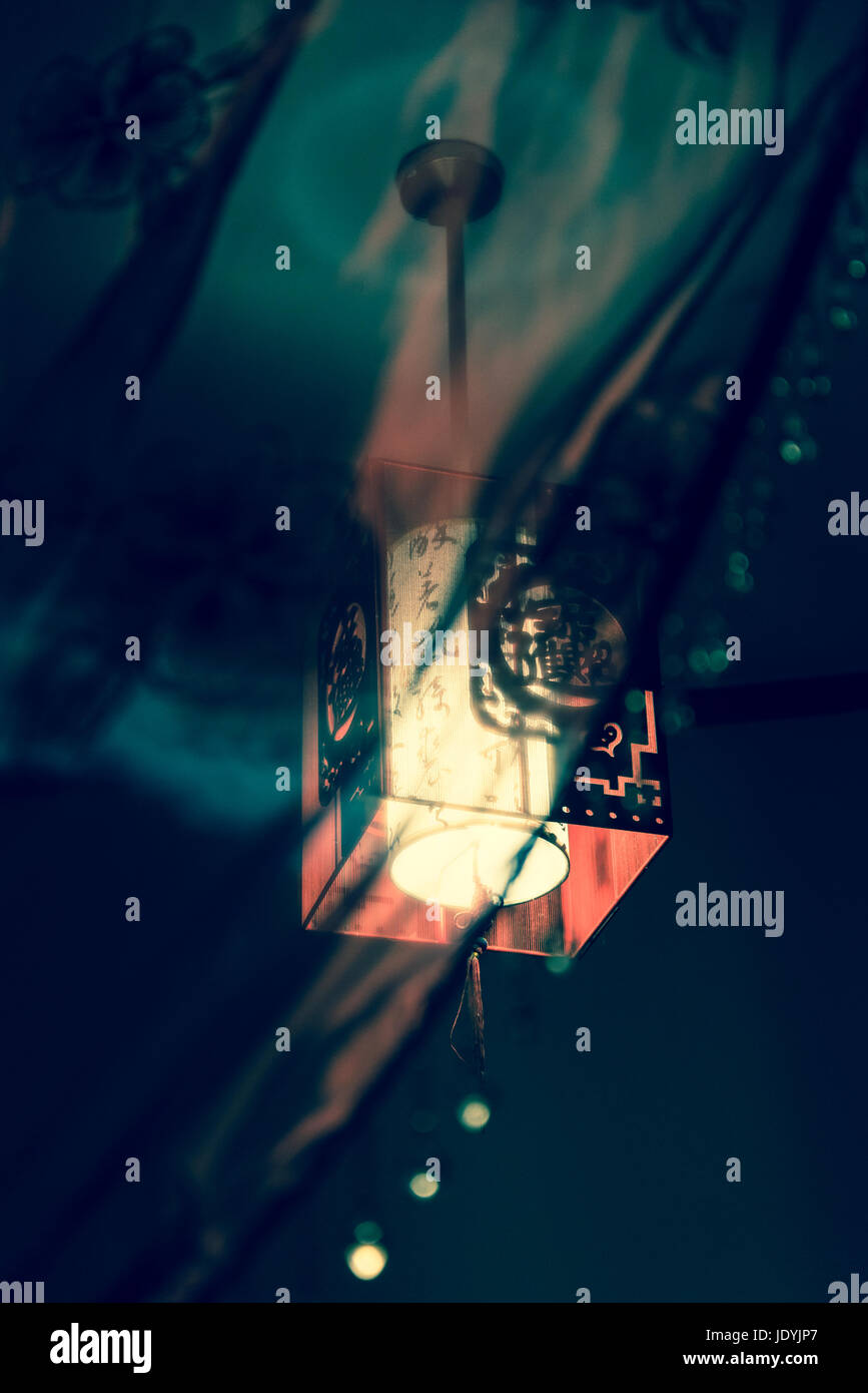 Lit chinese lantern in a darkened room Stock Photo