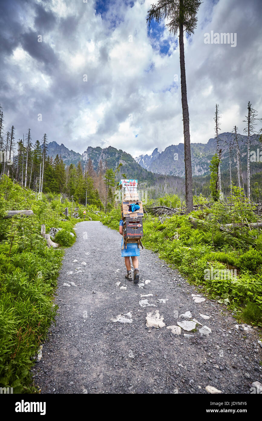 High Tatra Mountains, Slovakia - June 15, 2017: Mountain porter carrying heavy food supply to one of mountain huts. Stock Photo