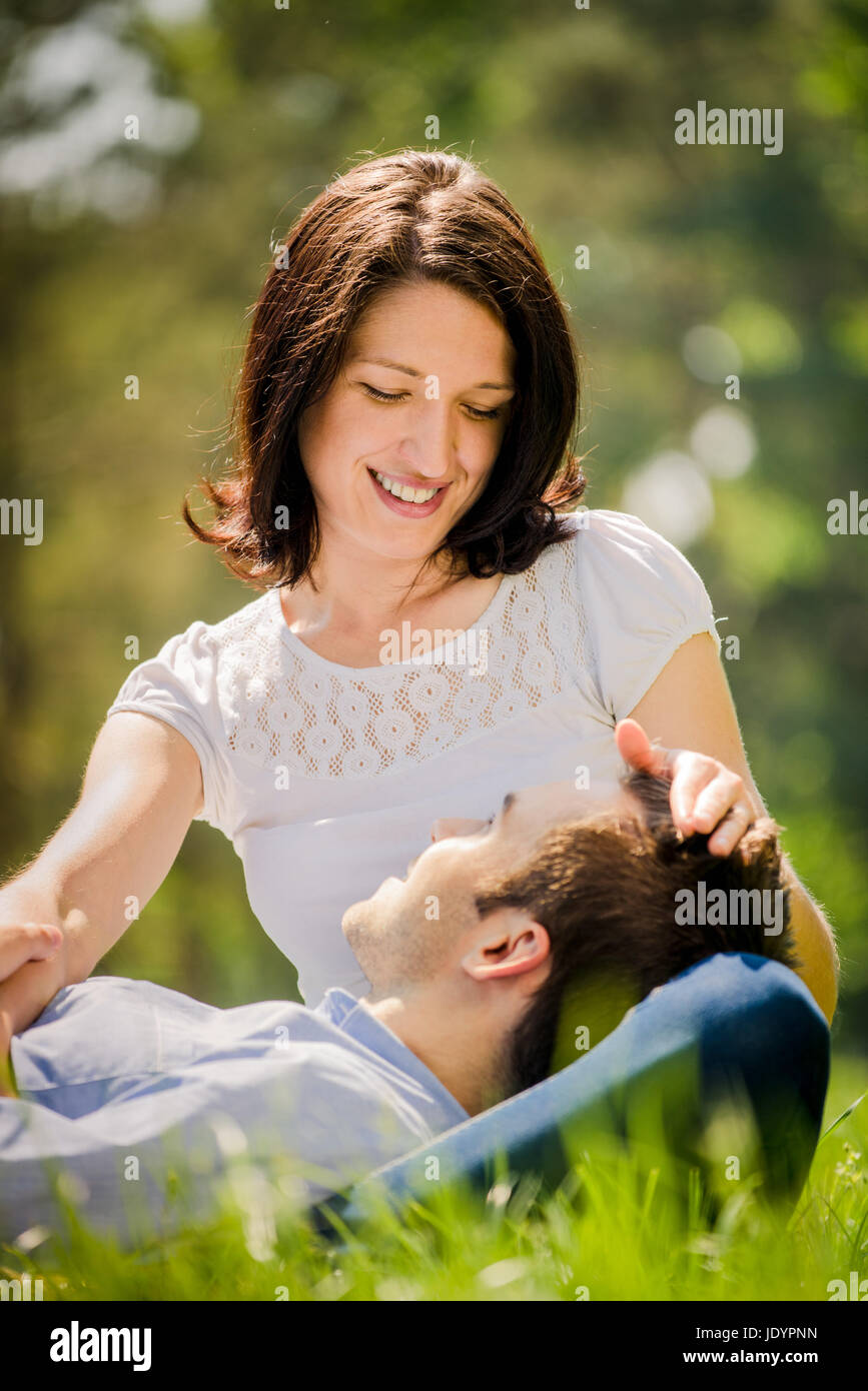 Young man is resting on woman's knees while she is caressing his hair Stock  Photo - Alamy