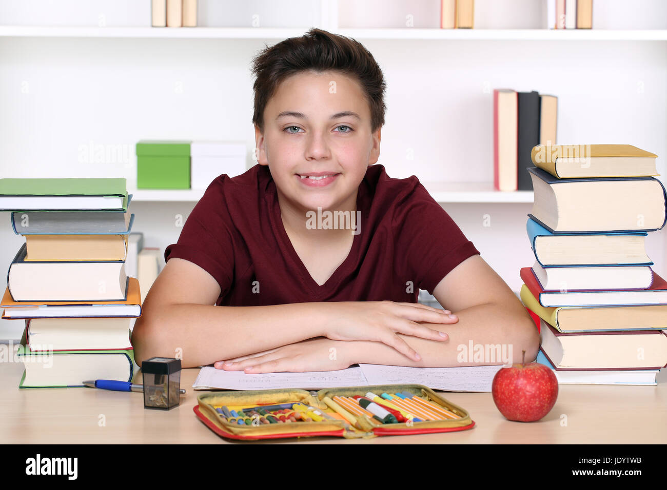 Lachender und glücklicher Junge macht Hausaufgaben in der Schule in sein Schulheft Stock Photo
