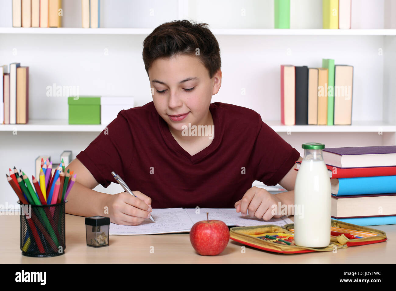 Junge beim Schreiben von Hausaufgaben in der Schule in sein Schulheft Stock Photo
