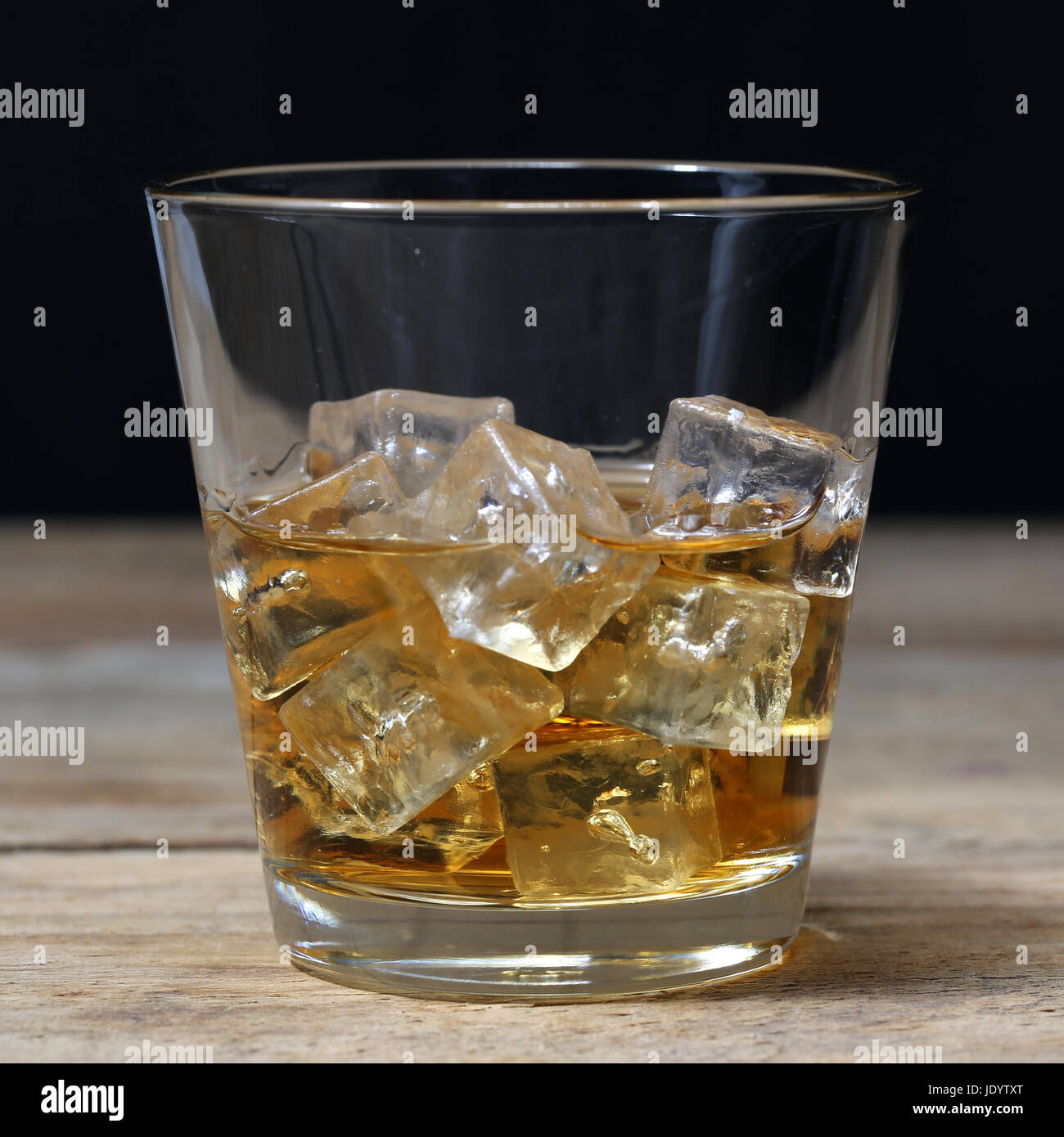 Whisky oder Whiskey im Glas mit Eiswürfeln auf einem Holzbrett Stock
