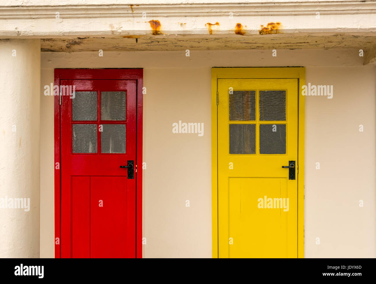 Row of colourful old wooden changing cubicle doors in primary colours with square window panes North Berwick harbour, East Lothian, Scotland, UK Stock Photo
