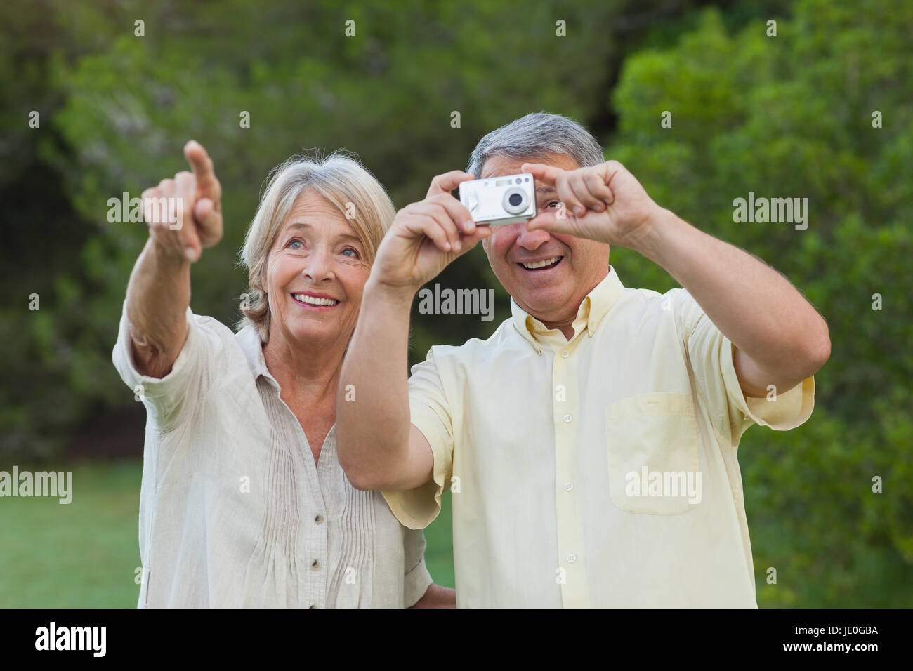 Happy older couple taking a photo of something in the park Stock Photo