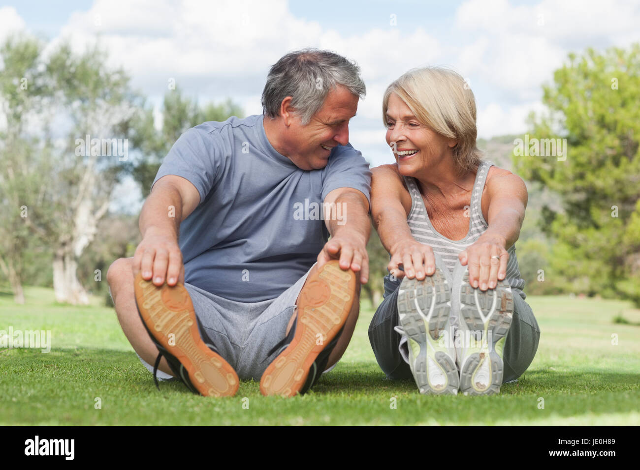 Happy older couple stretching in the park before exercising Stock Photo ...