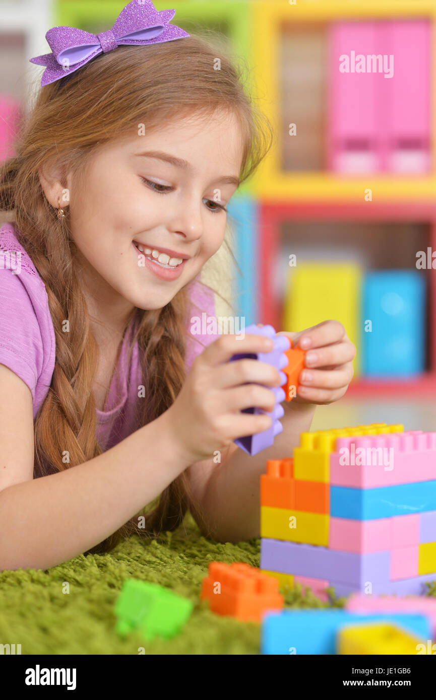 Cute girl playing with colorful plastic blocks in room Stock Photo - Alamy