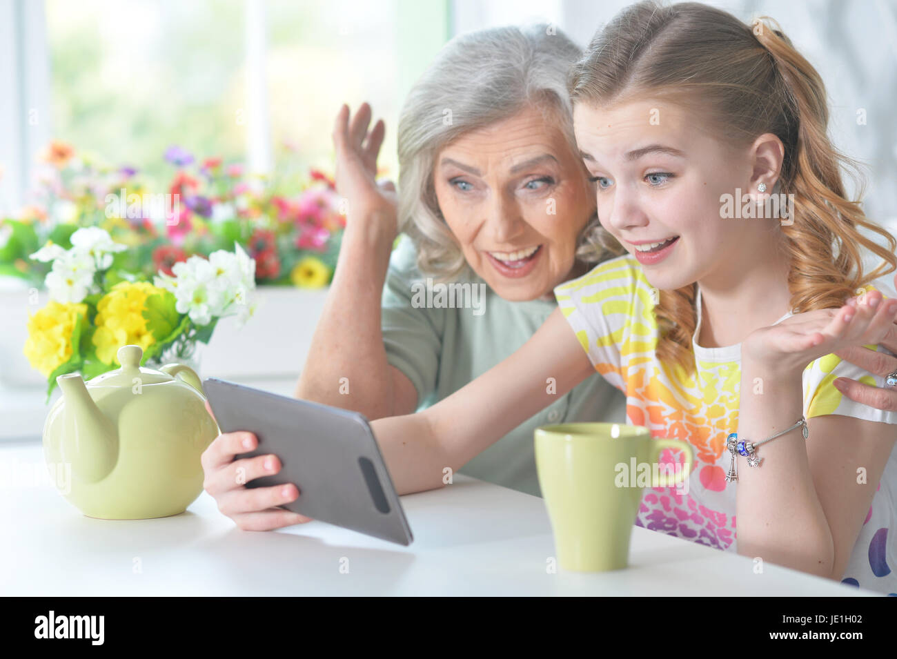 Cute little girl with her grandmother using tablet Stock Photo - Alamy