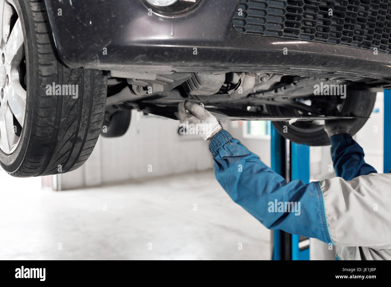 auto mechanic working under car on a lift. oil change Stock Photo Alamy