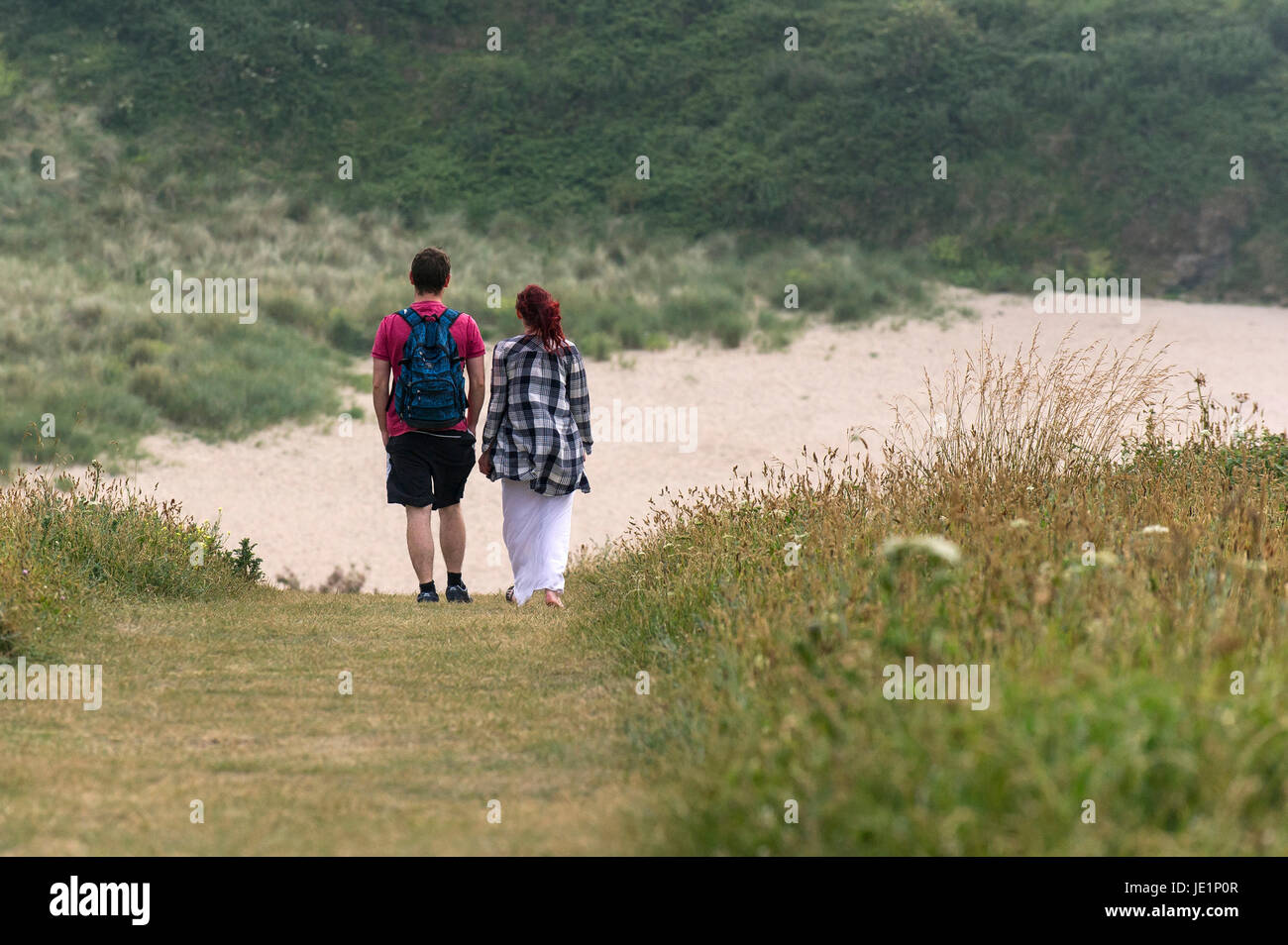 A couple walking along a footpath towards Polly Joke (Porth Joke) on the North Cornwall coast. Stock Photo