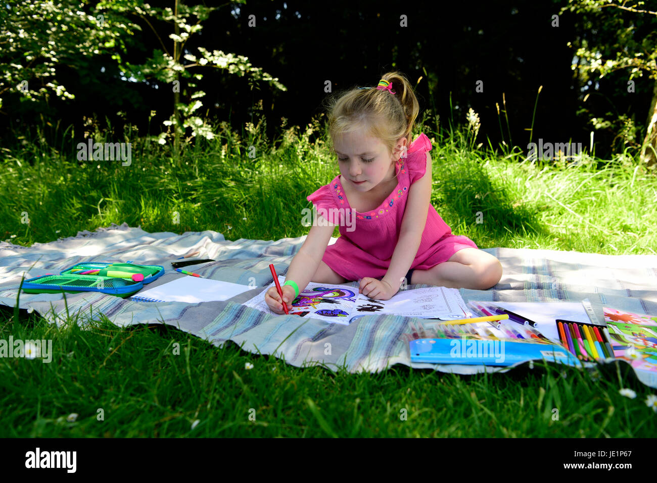 4 year old girl outdoors using colouring pens, Greatham, Hampshire, UK. 17 June 2017. Stock Photo