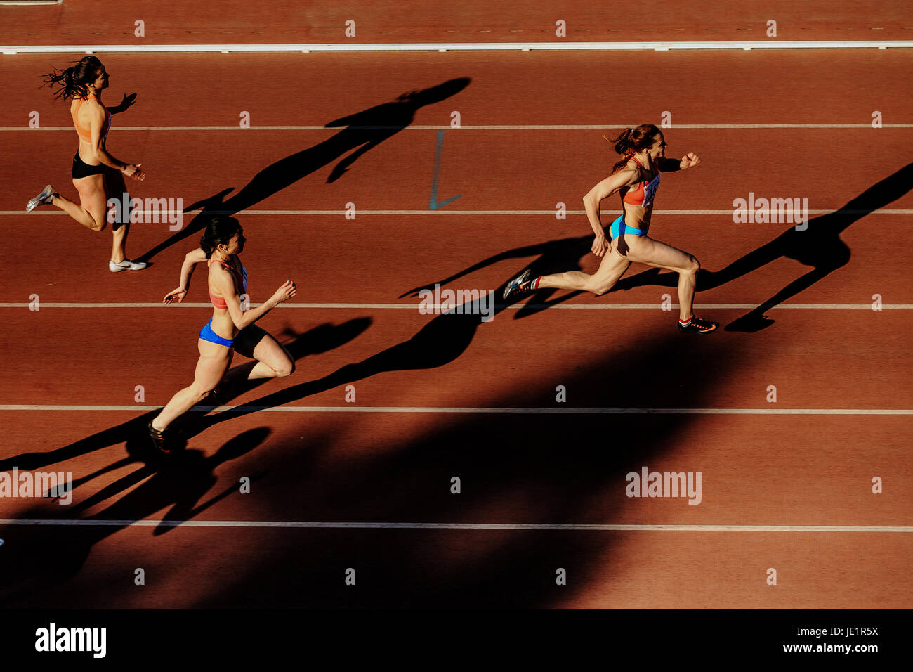three women runners shadows running sprint race during UrFO Championship in athletics Stock Photo