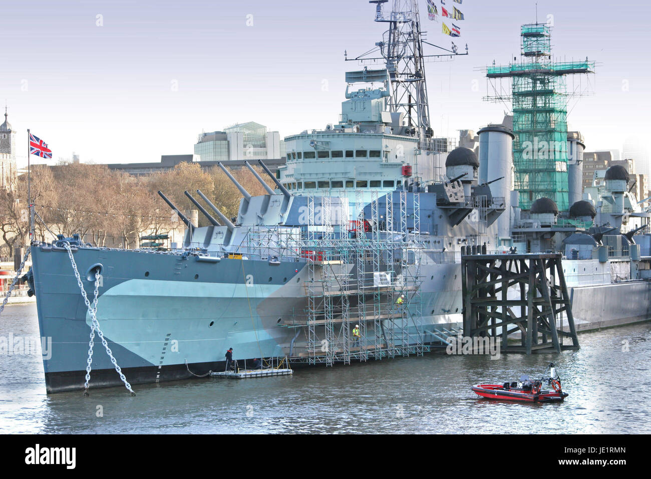 Scaffolding is suspended along the hull of museum ship HMS Belfast on the River Thames in London allowing painting and maintenance. Stock Photo