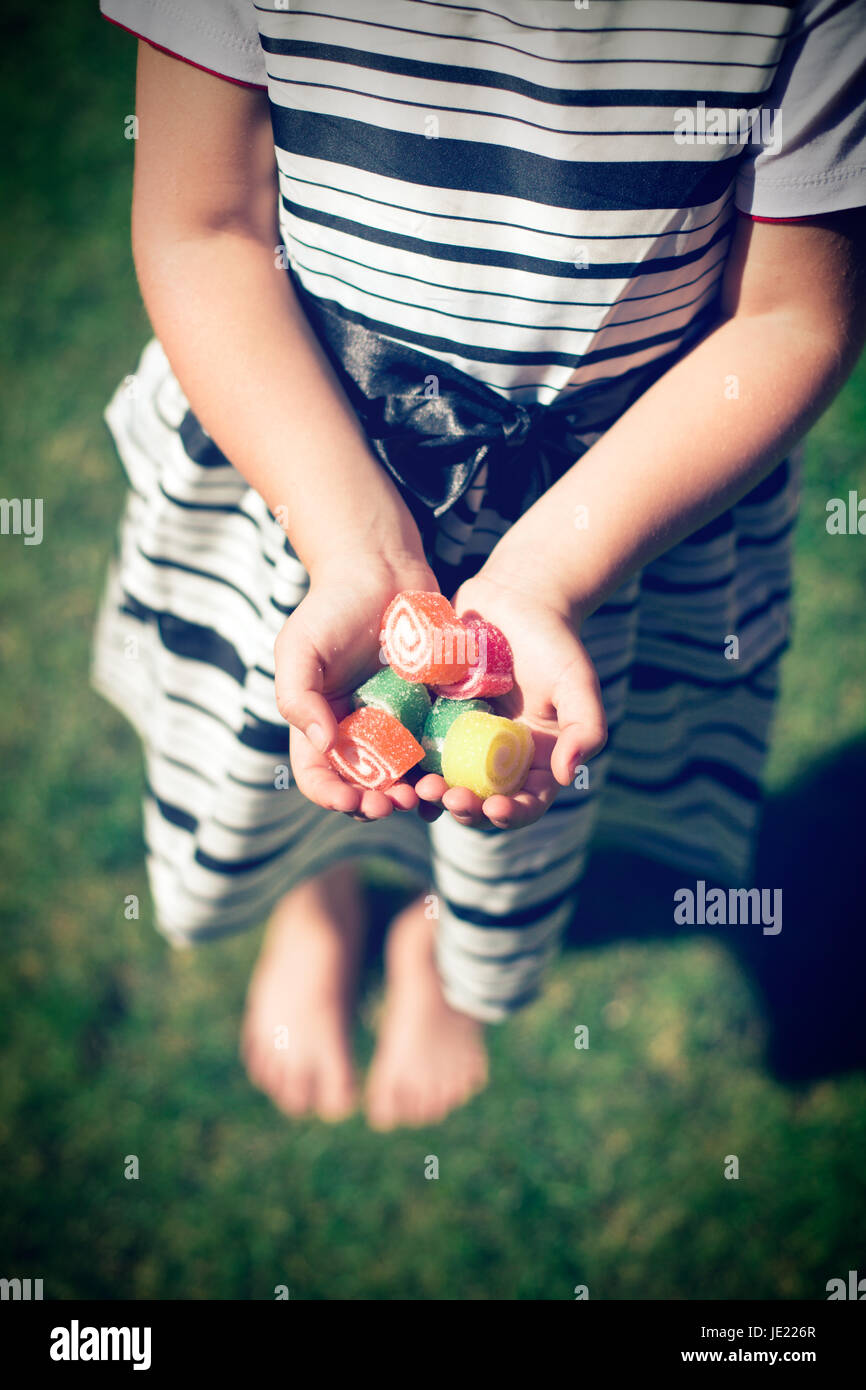 Little girl with candy in hands. Exterior shot. Stock Photo