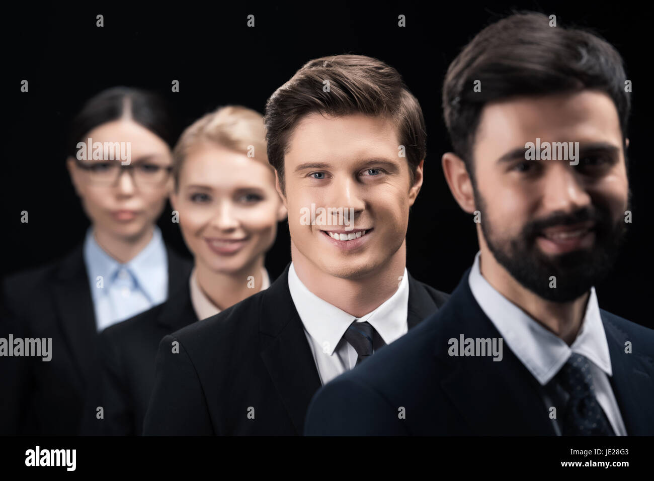 group of young business people standing in row isolated on black Stock ...
