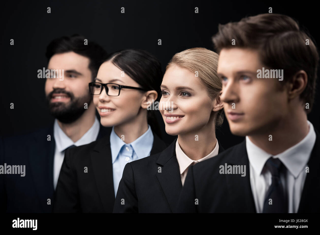 side view of business people standing in row isolated on black Stock ...