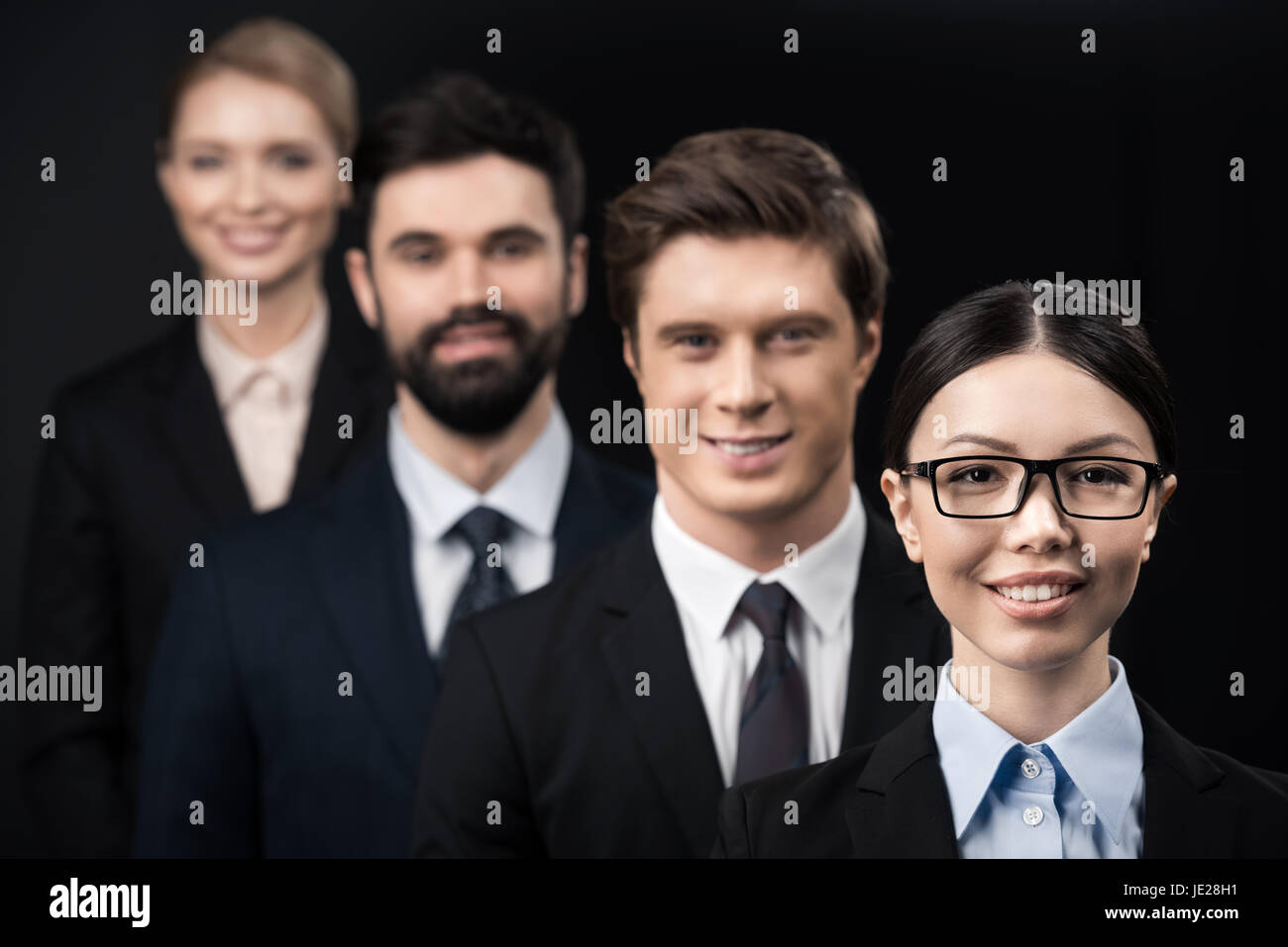 group of smiling business people standing in row isolated on black ...