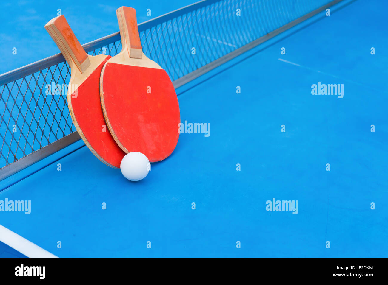 pingpong rackets and ball and net on a blue pingpong table Stock Photo