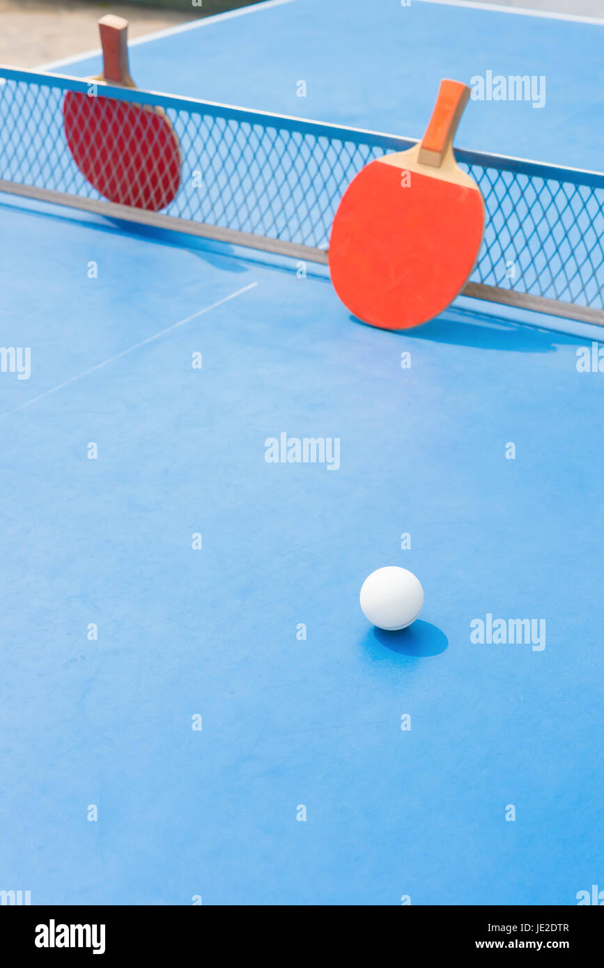 pingpong rackets and ball and net on a blue pingpong table Stock Photo