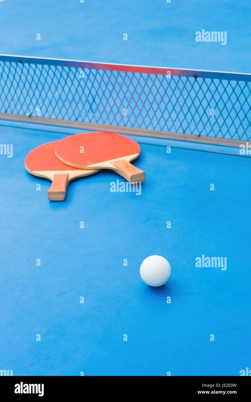 pingpong rackets and ball and net on a blue pingpong table Stock Photo