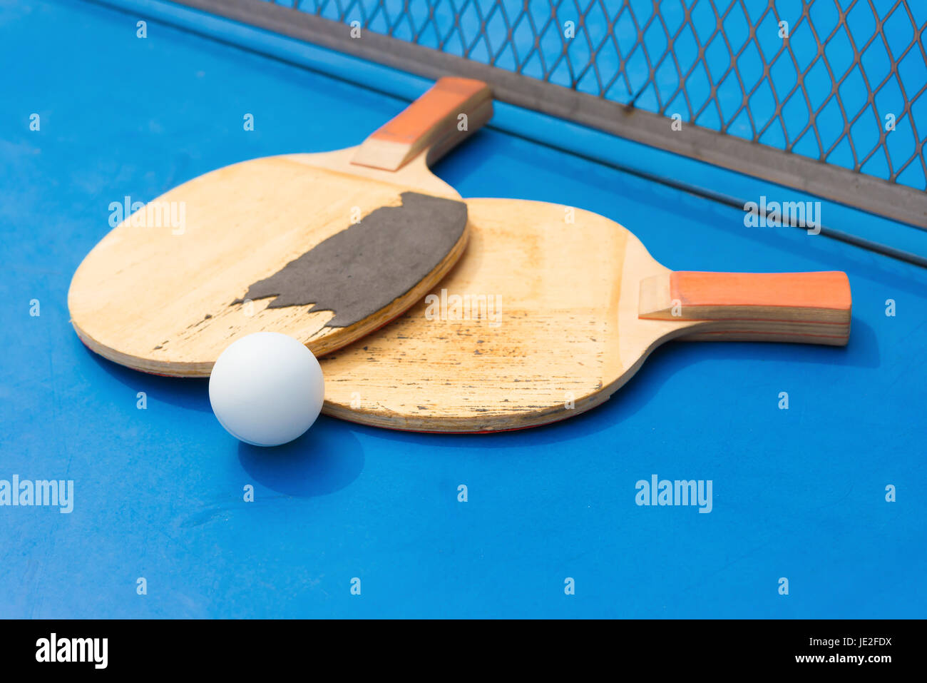 old pingpong rackets and ball and net on a blue pingpong table Stock Photo