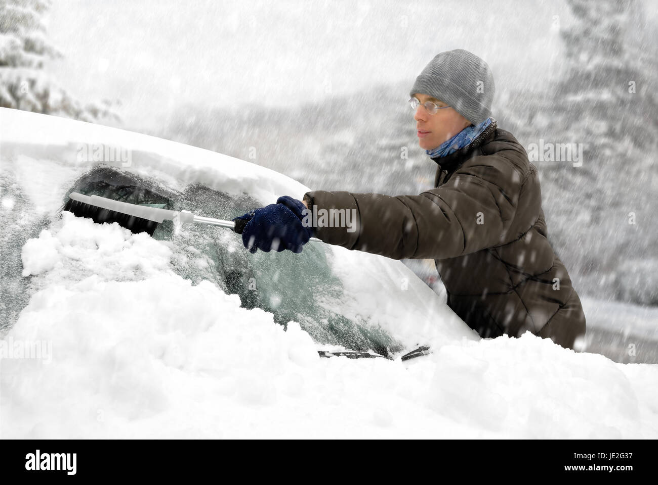 Junger Mann entfernt den Schnee von seinem Fahrzeug Stock Photo