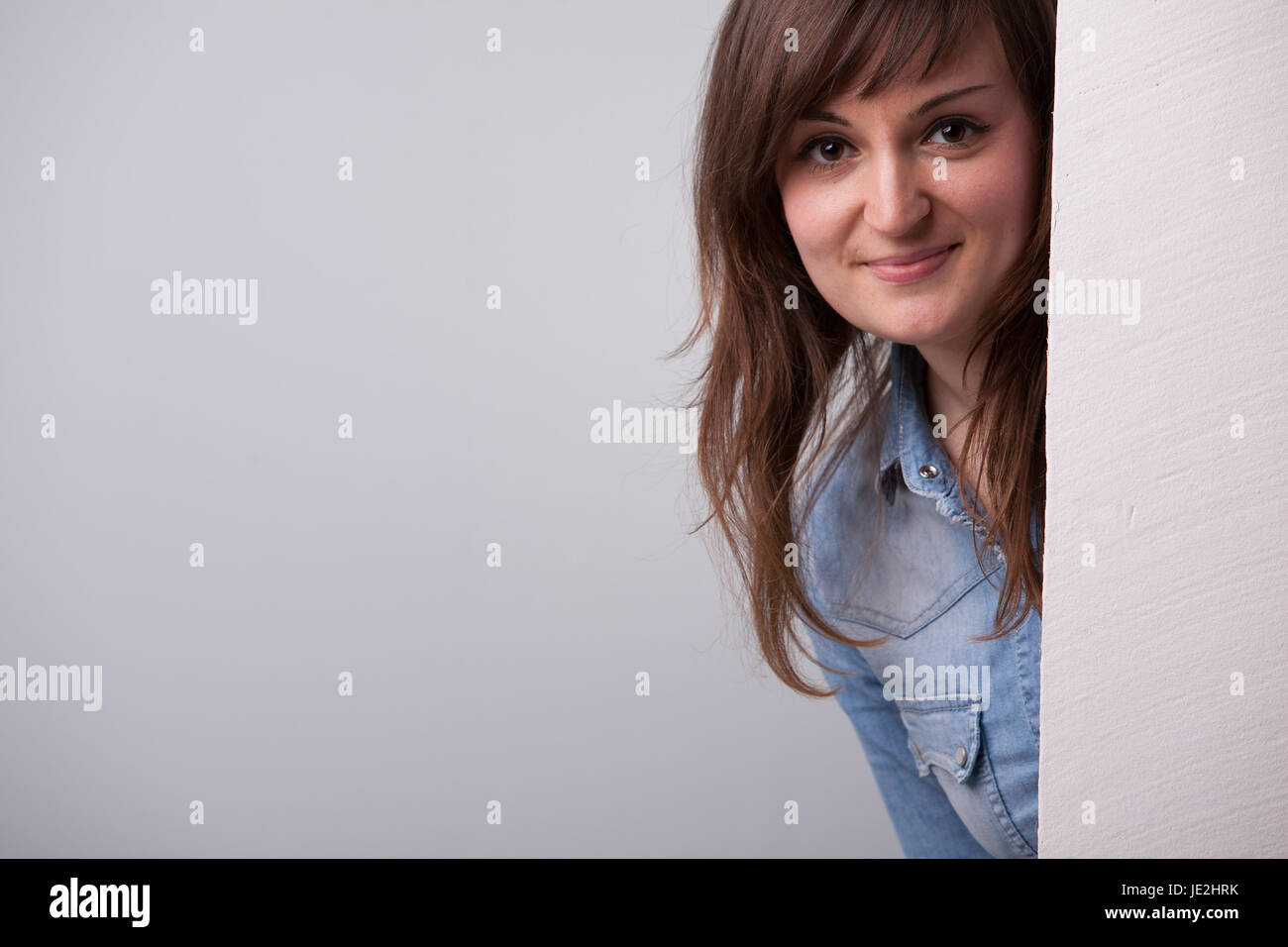 Nice girl showing up behind the white wall Stock Photo - Alamy
