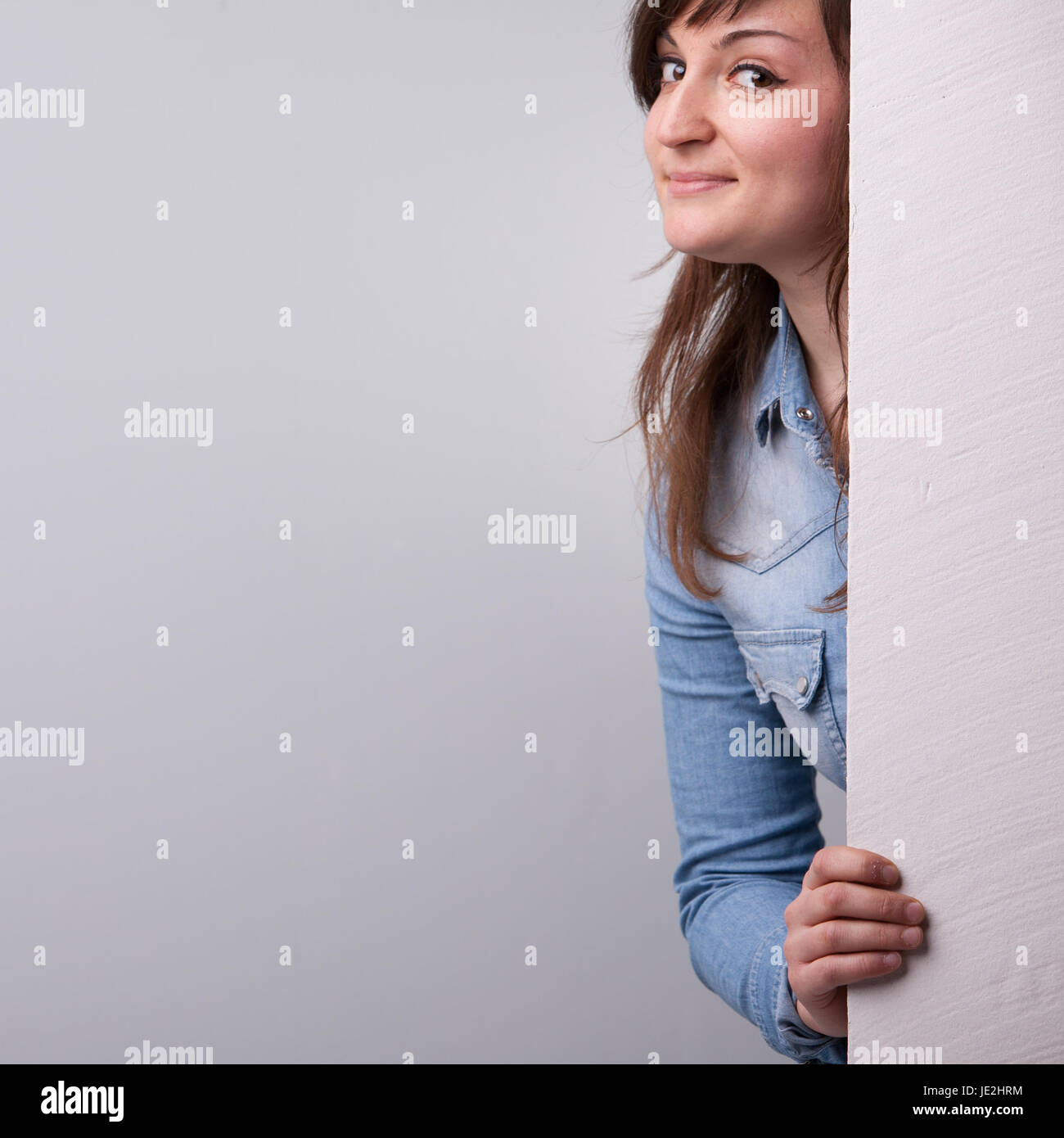 Nice girl showing up behind the white wall Stock Photo - Alamy