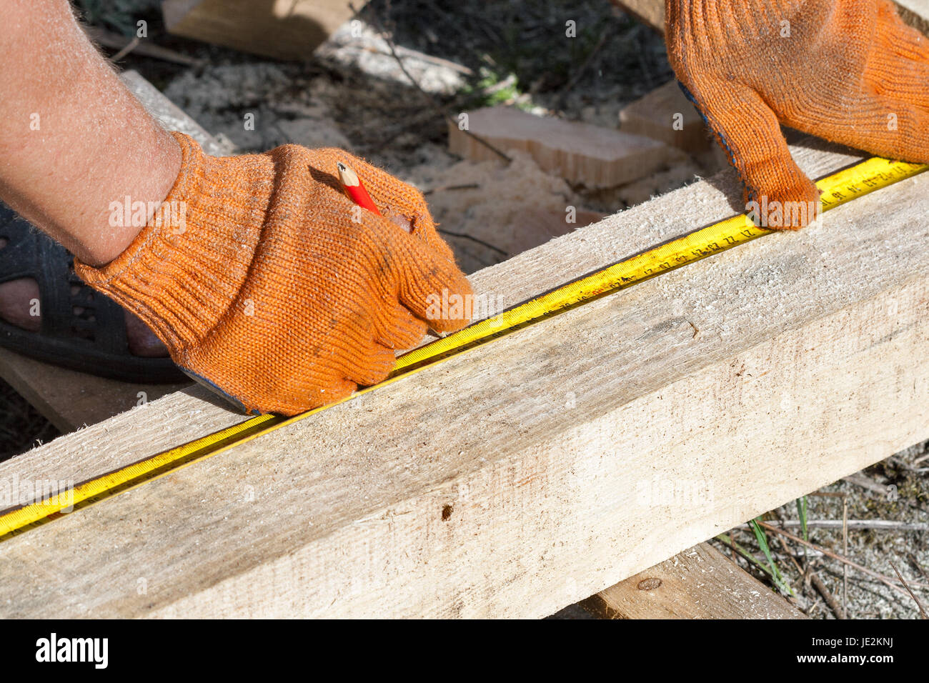 Construction wooden cottage. Measuring pine bars with the help of a vintage yardstick tool outdoor closeup. Stock Photo
