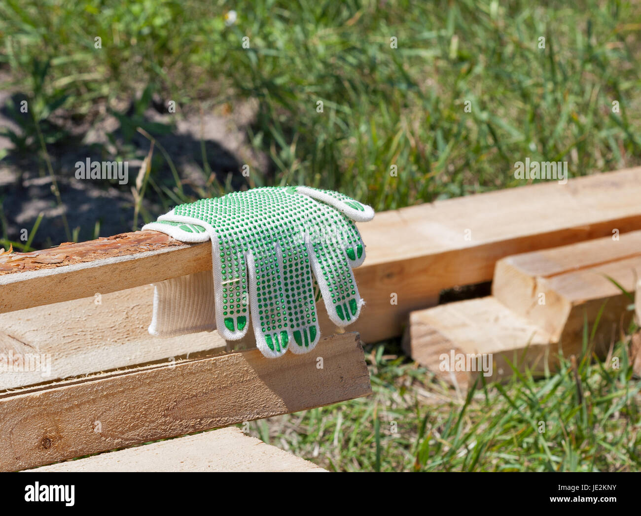 Construction wooden cottage. Processed pine bars with new work gloves outdoor closeup. Stock Photo