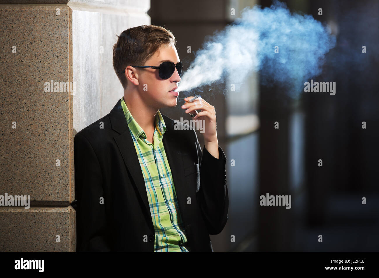 Young fashion man in sunglasses smoking a cigarette Stock Photo