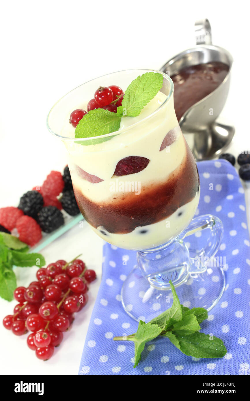 ein Dessert im Glas, geschichtet mit Pudding, roter Grütze und Beeren ...