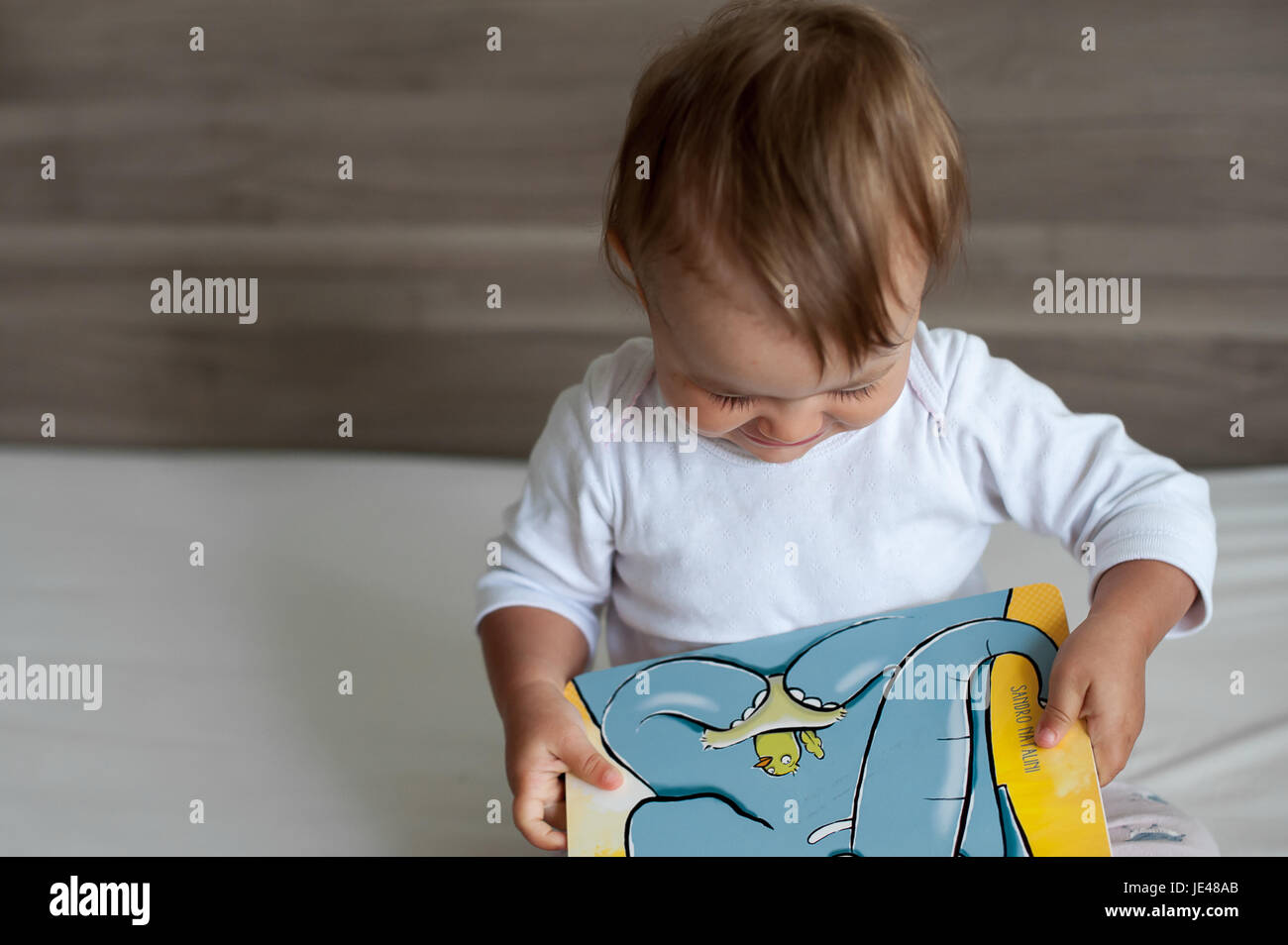 One year old infant looking at at a colorful children´s book. Stock Photo