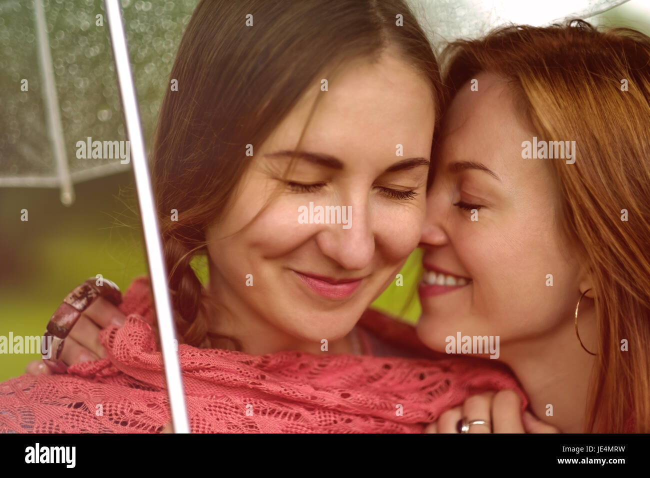 Two young beautiful women secret at summer green park Stock Photo