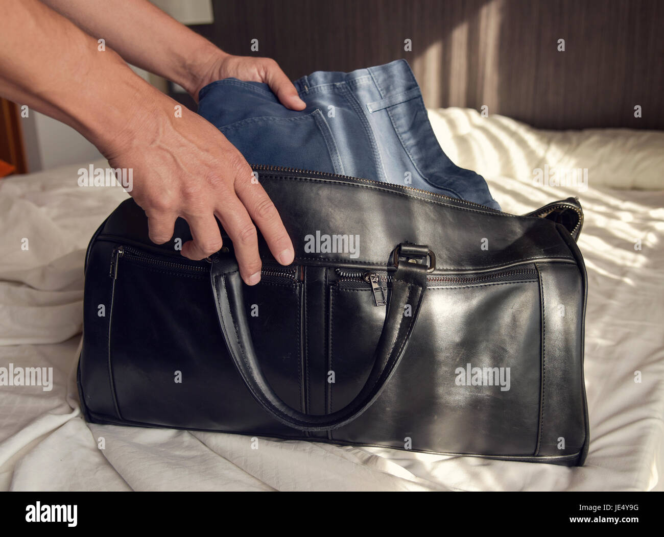 closeup of a young caucasian man putting clothes in a travel bag or