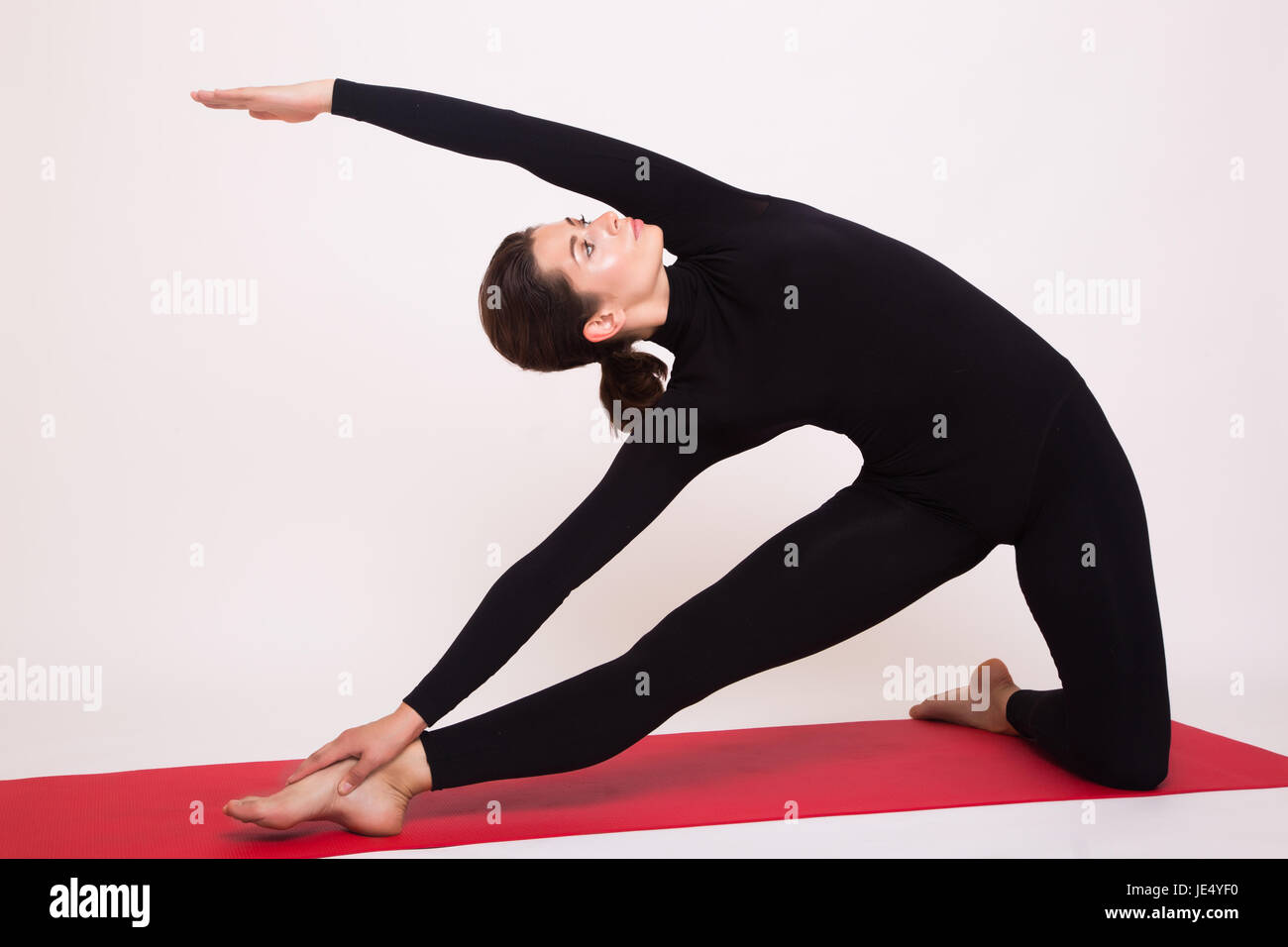 Beautiful athletic girl in black suit doing yoga asanas. Isolated on white background. Stock Photo