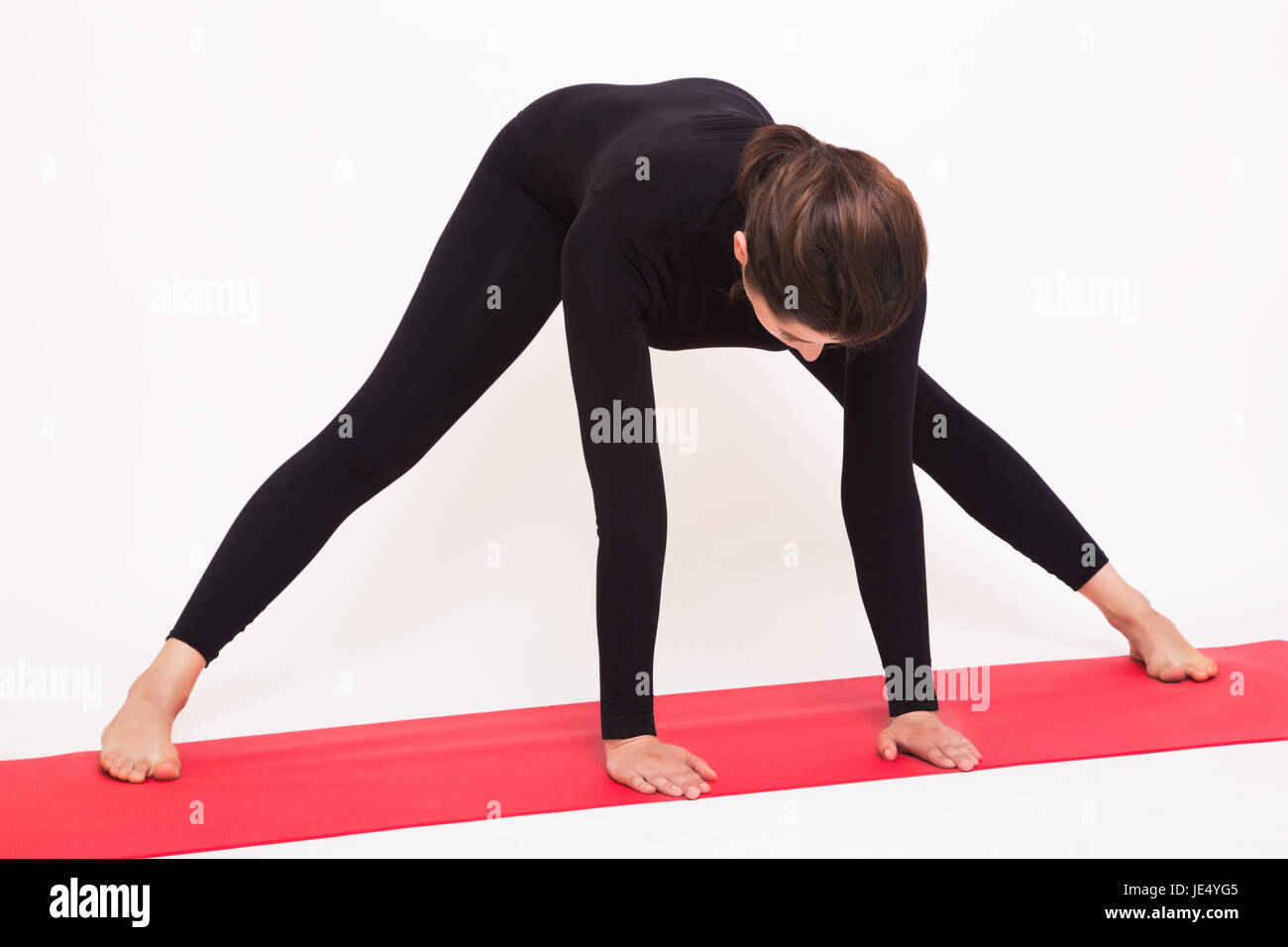 Beautiful athletic girl in black suit doing yoga asanas. Isolated on white background. Stock Photo