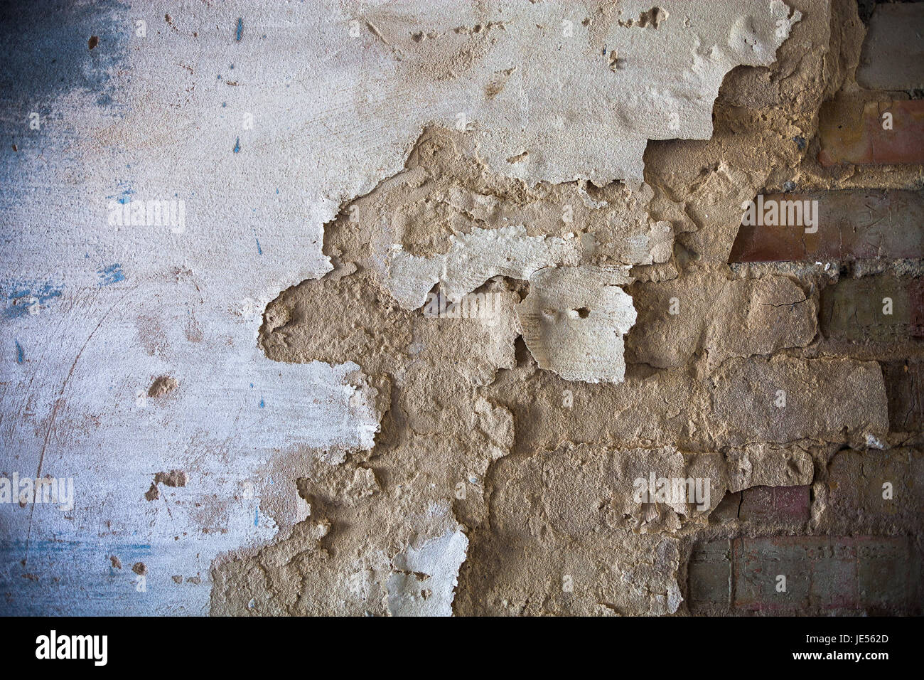 Damaged whitewashed plaster on the brick wall. Stock Photo