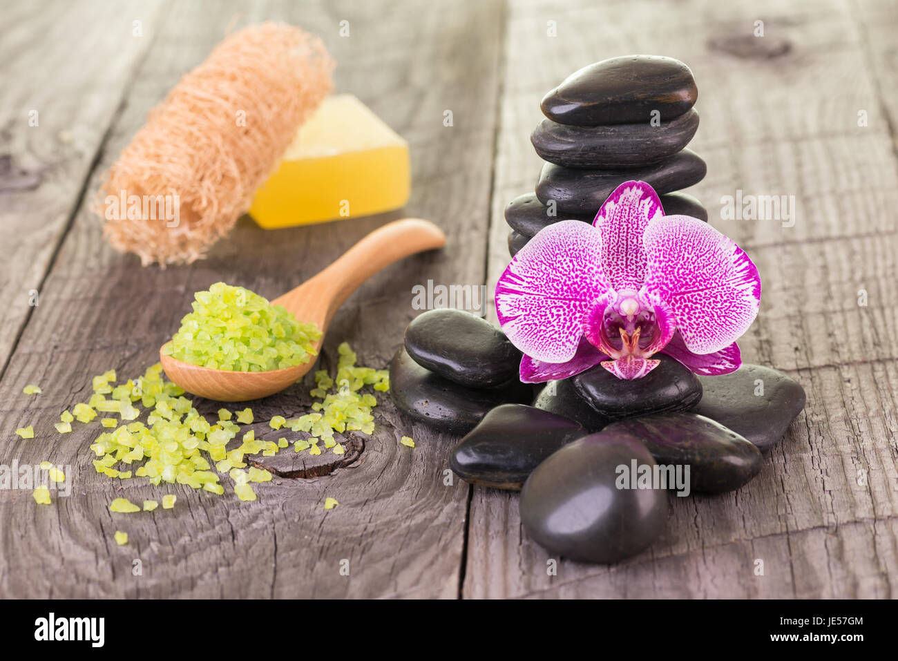 Fucsia moth Orchid and black stones on weathered deck Stock Photo