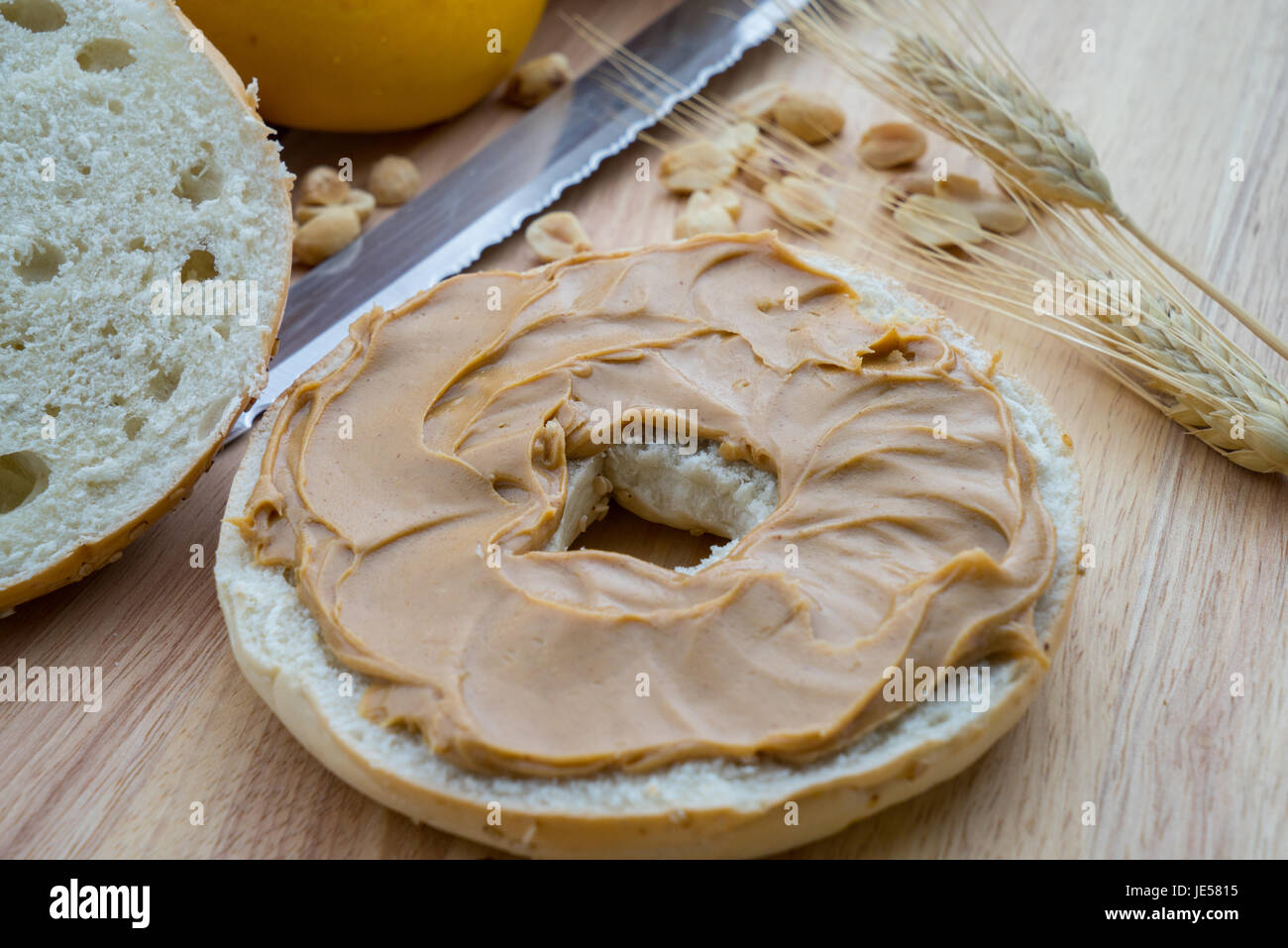 Sesame Bagel with Peanut Butter on a cutting board with knife Stock Photo