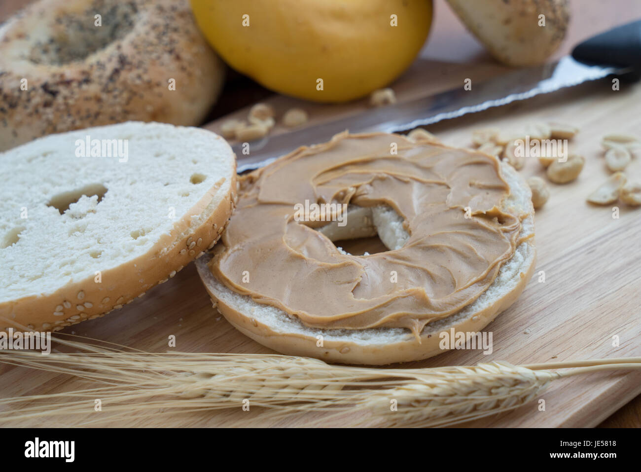 Sesame Bagel with Peanut Butter on a cutting board with knife Stock Photo