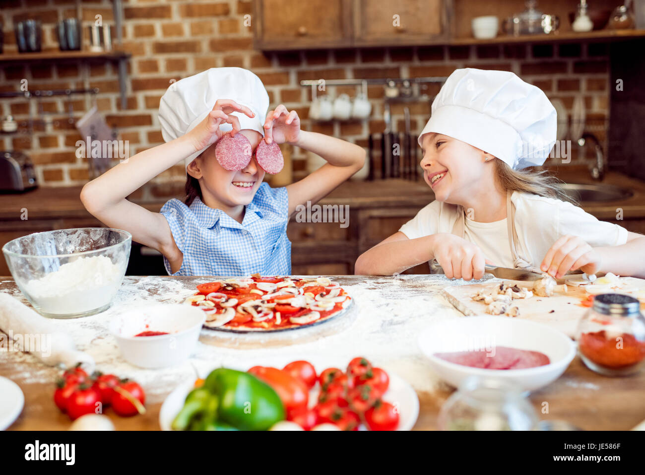 kids in chef hats having fun while making pizza Stock Photo