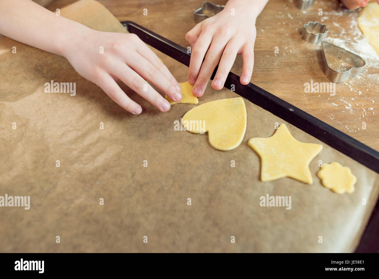 partial view of little kids making shaped cookies in kitchen Stock Photo