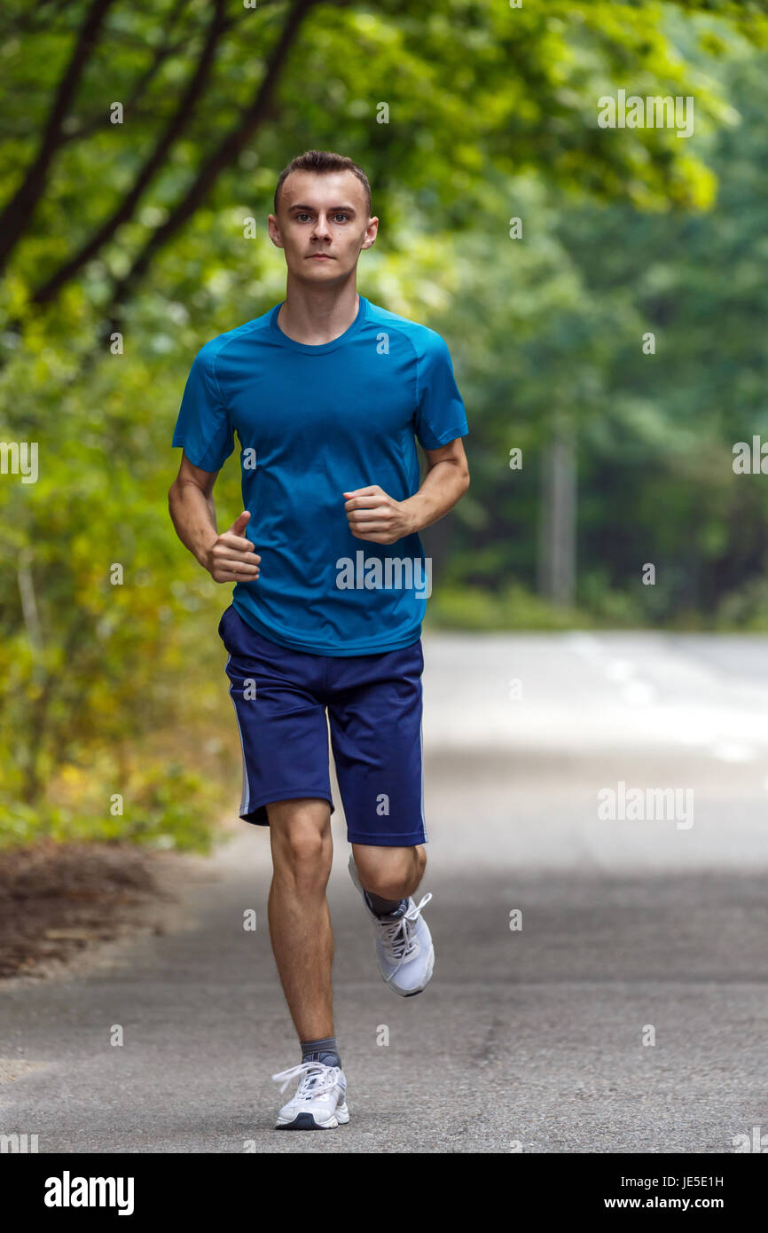 Young boy running outdoor through the forest on a road Stock Photo - Alamy