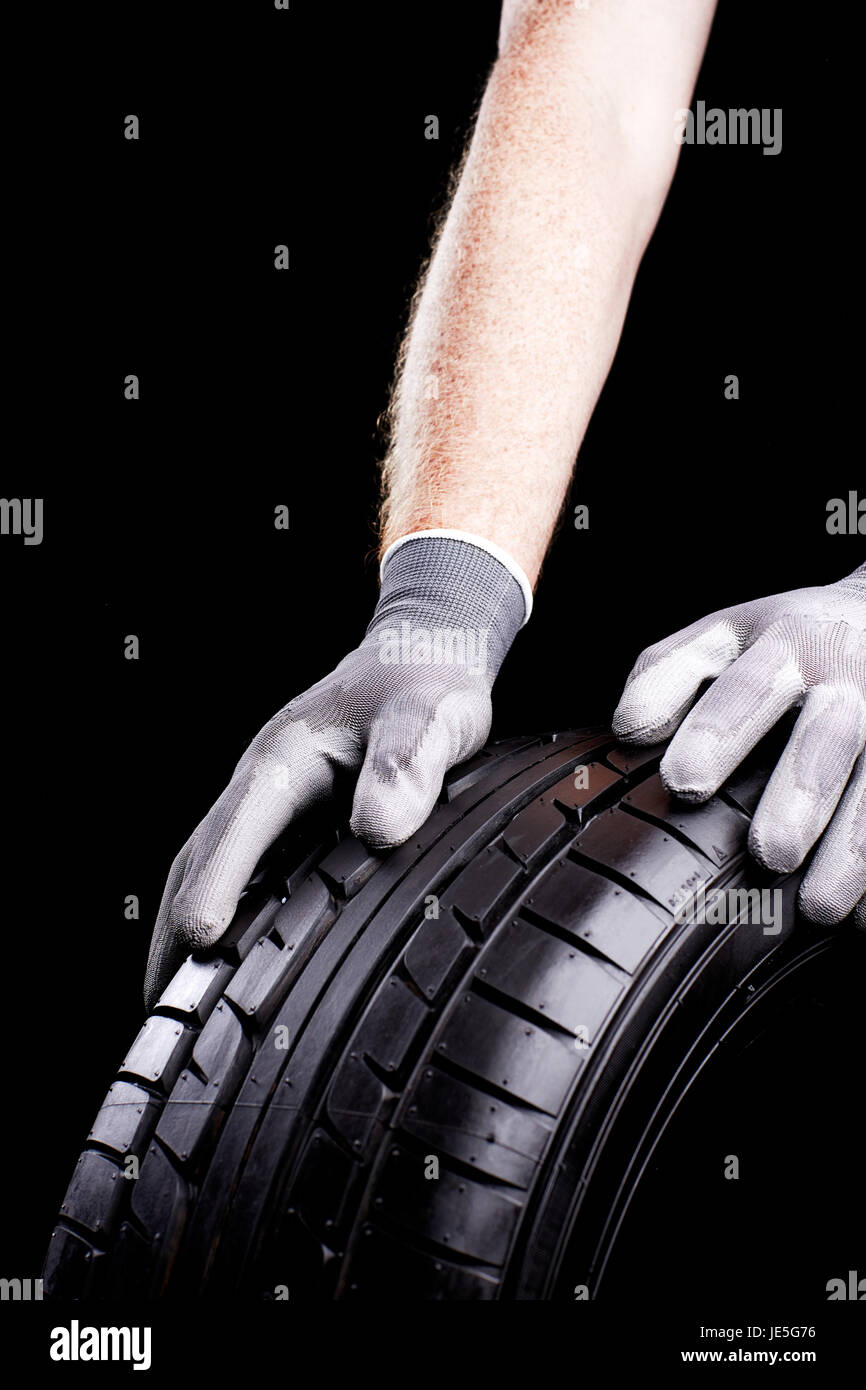 workers hands rolling tires in garage Stock Photo