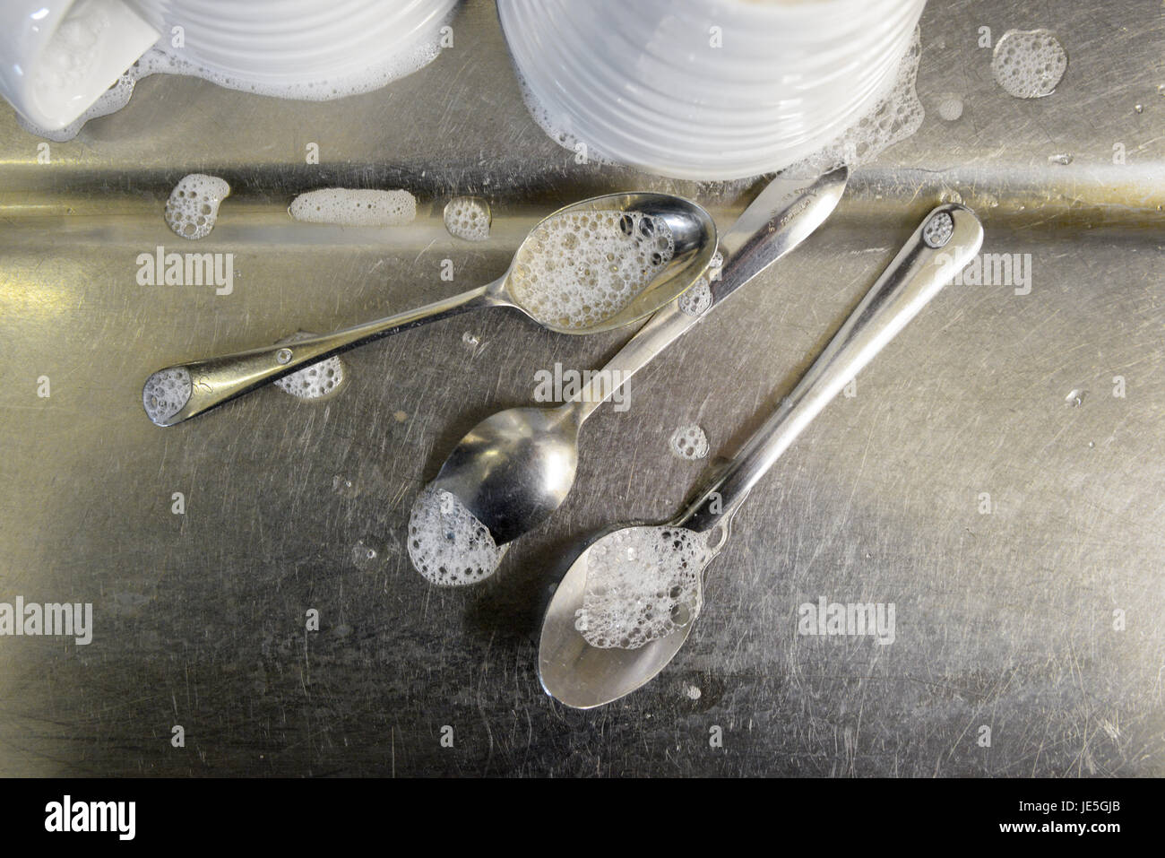 https://c8.alamy.com/comp/JE5GJB/teaspoons-with-soap-bubbles-and-white-cups-on-stainless-steel-draining-JE5GJB.jpg