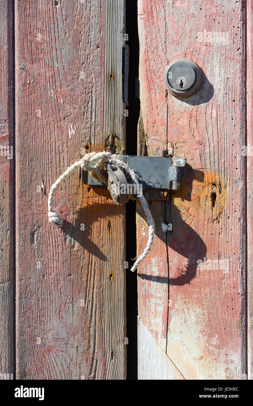 Decaying wooden garage doors secured with string and padlock. Stock Photo